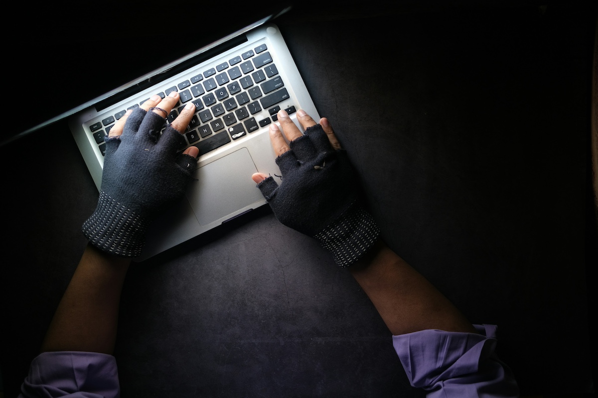 Gloved thief using a laptop